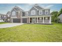 Charming two-story home featuring gray siding, brick accents, a welcoming front porch, and a two-car garage at 10903 Greenleaf Dr, Indianapolis, IN 46229