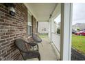 Inviting front porch with classic brickwork, white columns, seating, and a decorative front door at 10903 Greenleaf Dr, Indianapolis, IN 46229