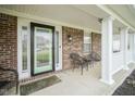 Inviting front porch with classic brickwork, white columns, seating, and a decorative front door at 10903 Greenleaf Dr, Indianapolis, IN 46229