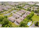 Aerial view of community featuring townhouses, a pond with fountains, green spaces, and a swimming pool at 11872 Salerno Ct, Carmel, IN 46032