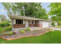 Charming home exterior showcasing brick accents, a covered porch, and a well-kept lawn with landscaping at 1410 Lawrence Ave, Indianapolis, IN 46227