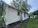 Side view of the home exterior featuring neutral siding, a window, green lawn, and trees at 1720 E Cornell Ave, Muncie, IN 47303