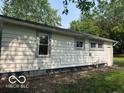 View of the home exterior featuring neutral siding, trimmed windows, and a green lawn at 1720 E Cornell Ave, Muncie, IN 47303