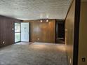 Spacious living room featuring neutral carpet, wood paneled walls, and a front door entrance at 2017 Schwier Ct, Indianapolis, IN 46229