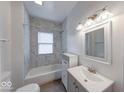 Well-lit bathroom featuring marble tile surround, modern vanity, and tub at 244 W 31St St, Indianapolis, IN 46208