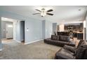 Open-concept living room with plush carpeting, ceiling fan, and modern furnishings flowing into the kitchen at 3010 Underwood Ct, Whiteland, IN 46184