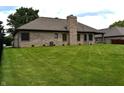 Spacious backyard with lush green grass, fenced in on one side with a brick chimney feature at 4723 Goldenrain Ct, Indianapolis, IN 46237