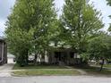 Traditional two-story home partially obscured by mature trees; features a welcoming covered porch at 48 N Audubon Rd, Indianapolis, IN 46219