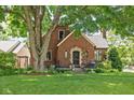 Charming brick home featuring lush green lawn and mature trees enhancing the curb appeal at 6280 Washington Blvd, Indianapolis, IN 46220