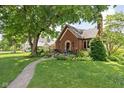 Charming brick home featuring lush green lawn and mature trees enhancing the curb appeal at 6280 Washington Blvd, Indianapolis, IN 46220