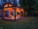 Cozy backyard patio with wooden pergola, string lights, and comfortable Adirondack seating, perfect for outdoor relaxation at 900 W Busby St, Lebanon, IN 46052