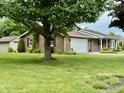 View of a well-maintained brick home showcasing a spacious front yard with mature trees at 9099 Ne Oak St, Alexandria, IN 46001