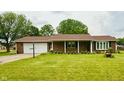 Charming brick home featuring a well-manicured lawn, attached garage, and decorative landscaping at 9099 Ne Oak St, Alexandria, IN 46001