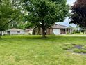 View of a well-maintained brick home showcasing a spacious front yard with mature trees at 9099 Ne Oak St, Alexandria, IN 46001