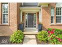 Inviting front entrance with elegant black door, sidelights, planters, and manicured landscaping at 9834 Belcrest Ln, Indianapolis, IN 46256