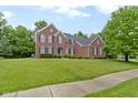 Beautiful two-story brick home featuring black shutters, a well-kept lawn, and lush landscaping at 11036 Ravenna Way, Indianapolis, IN 46236