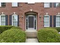 Charming front entrance framed by manicured shrubs, brick archway, and classic black shutters at 11036 Ravenna Way, Indianapolis, IN 46236