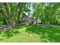Beautiful tree-lined lawn with a stately stone-and-brick home and a long driveway at 12380 Creekwood Ln, Carmel, IN 46032