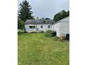 Rear view of home with small porch, showcasing yard and detached garage at 1609 N Outer Dr, Lebanon, IN 46052