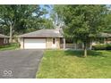 Single-story home with stone facade, attached garage and asphalt driveway with mature front yard landscaping at 1613 Park Rd, Anderson, IN 46011