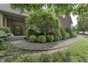 A sidewalk leads to the front entrance of a beautiful brick home with mature trees and landscaping at 2553 Forest Hills Blvd, Greenwood, IN 46143