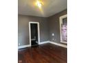 Empty living room with hardwood floors, brown walls, and natural light from a window at 319 S Temple Ave, Indianapolis, IN 46201