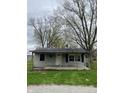 Charming single-story home with a covered porch, set against mature trees and a cloudy sky at 4206 Clark St, Anderson, IN 46013