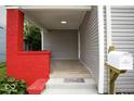 Inviting porch with bright red brick, wood-look tile, and a charming 'Home Sweet Home' doormat at 4923 E University Ave, Indianapolis, IN 46201
