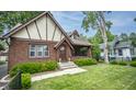 Inviting Tudor-style home with a brick facade, arched entryway, and well-kept front lawn at 5024 N Kenwood Ave, Indianapolis, IN 46208