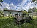 View of back yard with weathered wooden deck and siding, under a blue cloudy sky at 516 Memorial Dr, Edinburgh, IN 46124