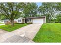 Inviting single-story house with a long driveway, attached garage, and lovely landscaping at 6310 Kellum Dr, Indianapolis, IN 46221