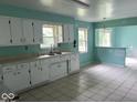 Kitchen with white cabinets, tiled flooring, and view into a room beyond a partial wall at 8045 Briarwood Dr, Indianapolis, IN 46227