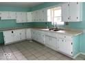 Kitchen showcasing ample white cabinetry, laminate countertops, stainless steel sink, and tiled flooring at 8045 Briarwood Dr, Indianapolis, IN 46227