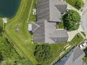 Aerial view of the house showing a backyard with mature trees, a small patio, and direct pond access at 10934 Harness Ct, Indianapolis, IN 46239