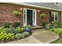 Close-up of front entrance with black door, hanging planters, and colorful potted flowers set in lush landscape at 11409 Haverstick Rd, Carmel, IN 46033