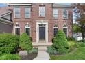 Close-up of the brick facade featuring a stylish front door flanked by manicured shrubs at 15515 Alameda Pl, Westfield, IN 46074