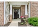 Inviting front porch with brick columns, flower arrangements and a decorative wreath at 1893 Devonshire Ave, Avon, IN 46123