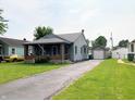 Exterior view of a quaint home with a detached garage and a long driveway at 2032 N Auburn St, Speedway, IN 46224