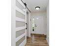 Bright entryway with modern sliding barn door, light wood floors, and a white front door at 293 E Quail Wood Ln, Westfield, IN 46074