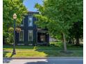 Two-story home with dark siding, white trim, and a manicured lawn with mature trees and flowering planters at 321 N Rangeline Rd, Carmel, IN 46032