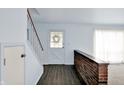 Bright foyer featuring wood floors, staircase, brick half wall, and natural light streaming in from sheer curtained window at 3425 Ireland Dr, Indianapolis, IN 46235