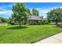Beautiful brick home with a lush green lawn, mature trees, and meticulous landscaping at 47 Oakwood Ct, Brownsburg, IN 46112
