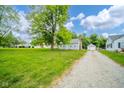 Landscaped front yard and long gravel driveway that leads to a detached garage at 5516 W Minnesota St, Indianapolis, IN 46241