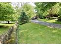 Scenic property view with stream, mature trees, manicured lawn, and driveway leading to the home at 6519 Creekside Ln, Indianapolis, IN 46220