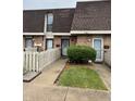 Inviting townhome exterior featuring a well-manicured lawn, picket fence, and brick facade at 7492 Country Brook Dr, Indianapolis, IN 46260