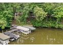 An aerial view of a lakefront house surrounded by lush trees and dock with several boats, offering serenity at 8133 Lower Bay Ln, Indianapolis, IN 46236