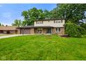 Charming home with a lush green lawn, mature trees, covered porch, and attached two-car garage at 955 Wood Creek Pl, Greenwood, IN 46142