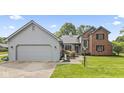 Charming two-story home with a grey garage, brick, beautiful landscaping, and a well-manicured lawn at 13153 Tudor Dr, Carmel, IN 46033