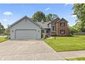 Charming home with two-car garage, concrete drive, lush lawn and landscaped front yard at 13153 Tudor Dr, Carmel, IN 46033