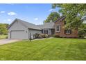 Charming home with two-car garage, lush lawn and beautiful landscaping with bright flowers at 13153 Tudor Dr, Carmel, IN 46033